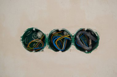 Plastik kapağı olmayan soketler, beton bir duvara monte edilmiş. İçine kablolar yerleştirildi