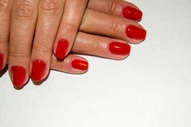 Kırmızı manikürlü ve ellerinde krem sürmüş bir kadının parmakları.