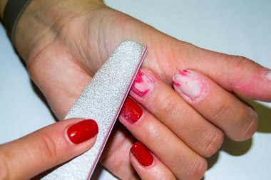 Çivi törpüleme işlemi. Kırmızı verniği kesiyorum. Kadın manikürü. Yakın plan.