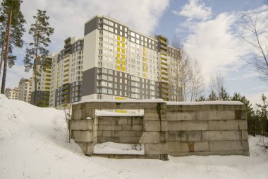 Karda bitmemiş beton bir yapı. Arka planda yeni bir konut binası var. Bitmemiş başlangıç ve bitiş