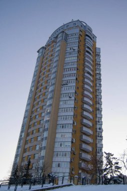 Gri gökyüzüne karşı çok katlı bir bina. Camdan balkonlu bir ev. karla kaplı dünya