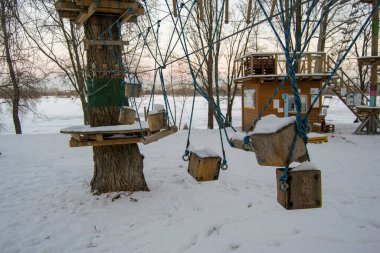 Ekstrem bir parkta ip izleri. İplerden sarkan tahta küpler. Küp üstüne kar