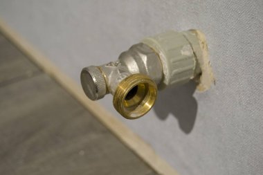 Radyatör bağlantı vanası. Musluk duvardan sarkıyor. Cevizi becermek için pirinç iplik.