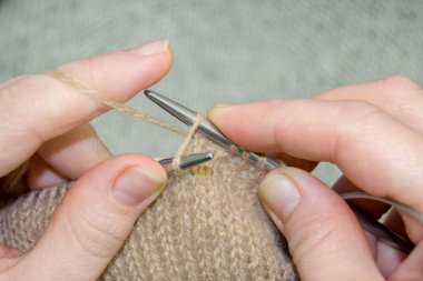 Kahverengi ipliklerden bir kazak örme süreci. Üretime yakın çekim. El yapımı.