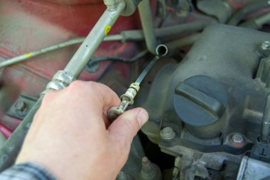 Bir adamın eli arabadaki yağ çubuğunu çıkartır. motordaki yağ seviyesini kontrol et