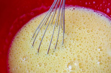 Karıştırıcı çırpıcılı sarı pasta kremi. Kremin yüzeyinde hava kabarcıkları var.