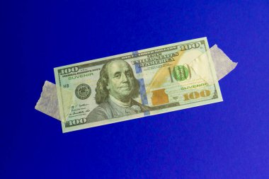 Boya bandıyla mavi arka plana iliştirilmiş hatıra dolar banknotu