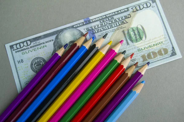 Hediyelik banknotların üzerine renkli kalemler. ögeler gri arkaplanda yatar