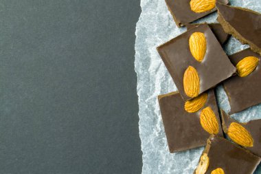 Beyaz kağıda badem sürülmüş çikolata. Siyah arkaplanı olan metin eklemek için bir yer. acı tatlılık