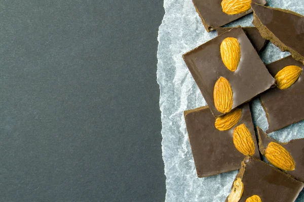 Beyaz kağıda badem sürülmüş çikolata. Siyah arkaplanı olan metin eklemek için bir yer. acı tatlılık