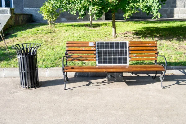 The solar panel is built into a wooden bench. A place to charge gadgets and relax. New technologies in the city