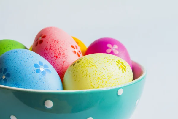 Colorful easter eggs in green spotted bowl on light background — Stock Photo, Image