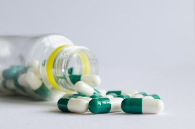 Yeşil ve beyaz hap üzerinde hafif backgr bir plastik kavanoz dışarı dökmek