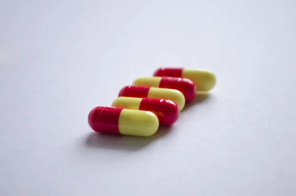 Five red and yellow capsules on a light background — Stock Photo, Image