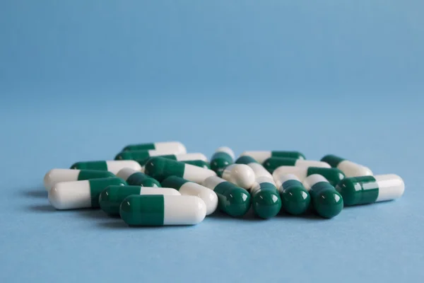 Green and white capsules on a blue background — Stock Photo, Image