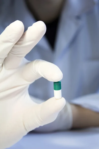 Close-up hand in medical rubber glove holding one green and whit — Stock Photo, Image