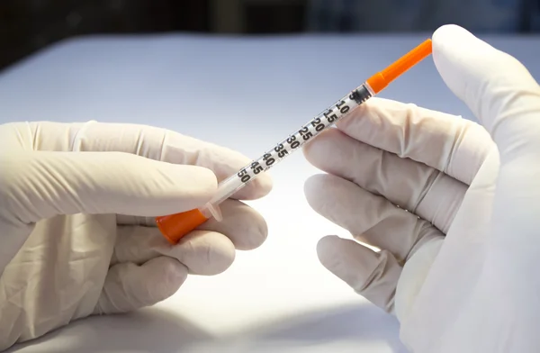 Hands in medical rubber gloves holding one insulin syringe — Stock Photo, Image