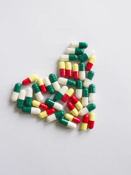 Heart-shaped bi-colored capsules on white background — Stock Photo, Image
