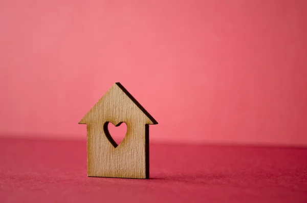 Wooden house with hole in the form of heart close-up on red back — Stock Photo, Image