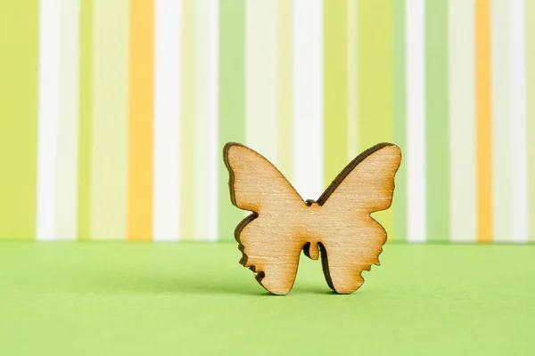 Wooden icon of butterfly on green striped background — Stock Photo, Image