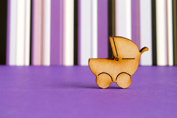 Wooden icon of baby carriage on purple striped background — Stock Photo, Image