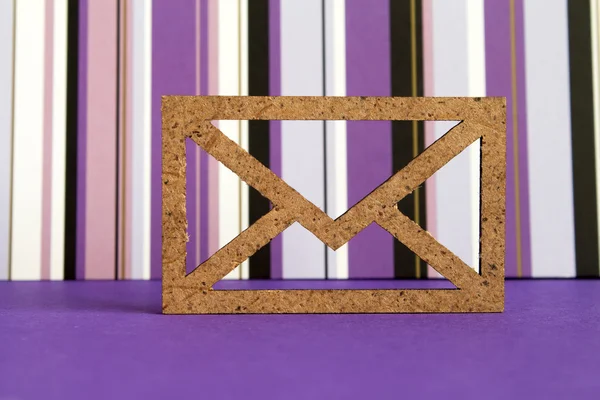 Icono de sobre de madera sobre fondo rayado púrpura — Foto de Stock