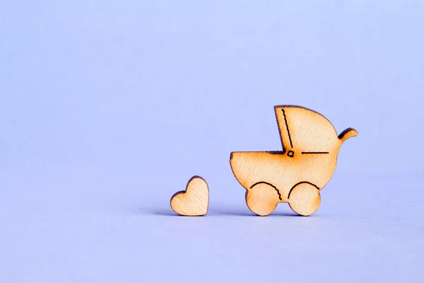 Wooden icon of baby carriage and little heart on purple backgrou — Stock Photo, Image