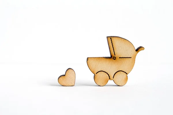 Деревянная икона детской коляски и маленькое сердце на белой спинке — стоковое фото