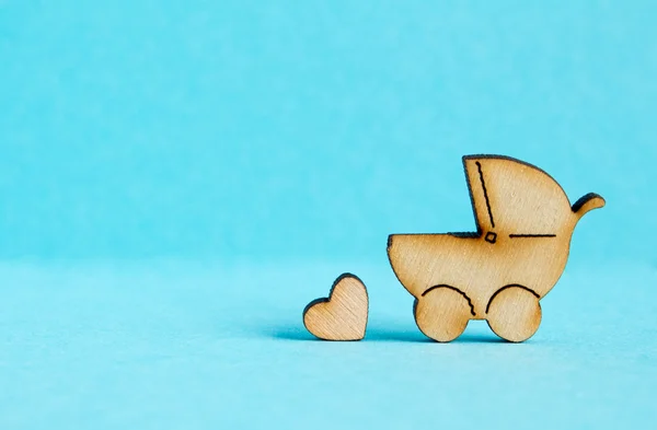 Ícone de madeira da carruagem do bebê e pouco coração no fundo azul — Fotografia de Stock