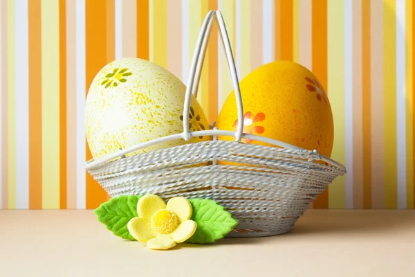 Huevos de Pascua amarillos y anaranjados en una cesta con flor amarilla — Foto de Stock