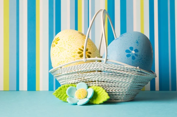 Uova di Pasqua gialle e blu in un cesto con fiore blu — Foto Stock