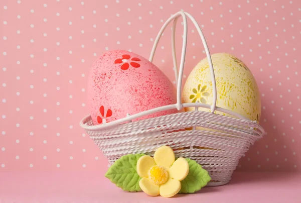 Huevos de Pascua rosados y amarillos en una cesta con flor amarilla — Foto de Stock