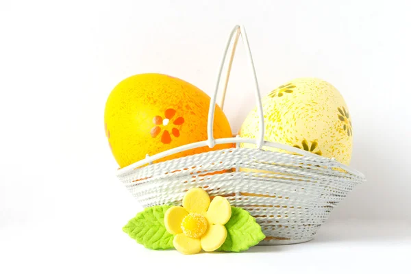 Oranžové a žluté velikonoční vajíčka v košíku s žlutým květem — Stock fotografie