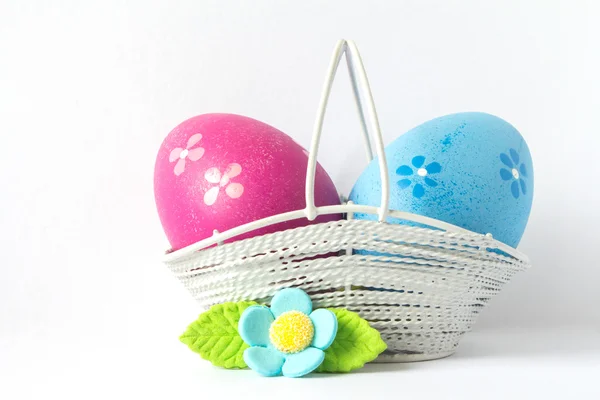 Huevos de Pascua rosados y azules en una cesta con flor azul — Foto de Stock