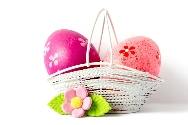 Pink and crimson Easter eggs in a basket with pink flower — Stock Photo, Image