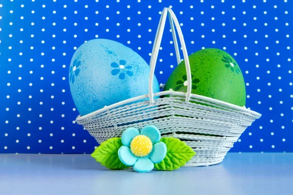Huevos de Pascua azules y verdes en una cesta con flor azul — Foto de Stock