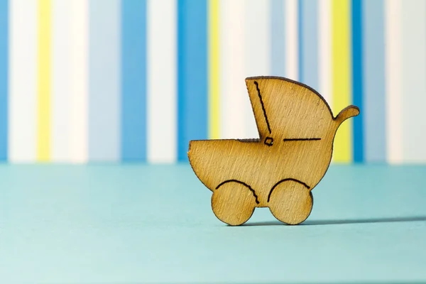 Wooden icon of baby carriage on blue striped background — Stock Photo, Image