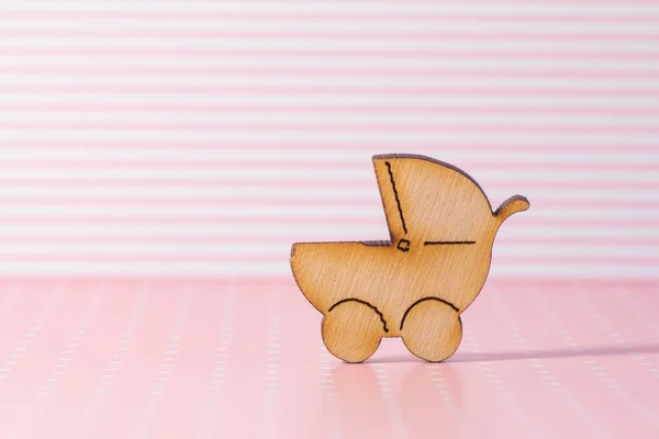 Wooden icon of baby carriage on pink striped background — Stock Photo, Image