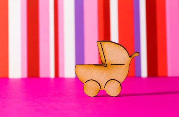Деревянная икона детской коляски на красном полосатом фоне — стоковое фото