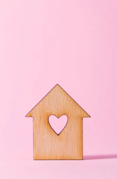 Wooden house with hole in the form of heart on pink background — Stock Photo, Image