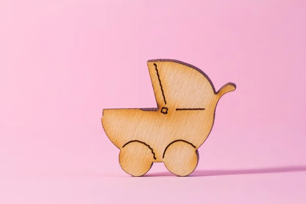 Wooden icon of baby carriage on pink background — Stock Photo, Image