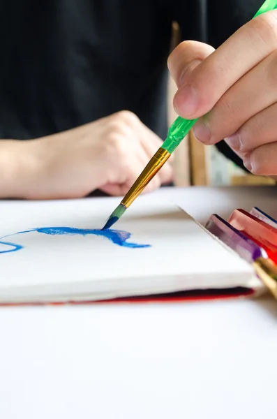 Mão esquerda desenha pincel com tinta azul em papel no álbum com sev — Fotografia de Stock