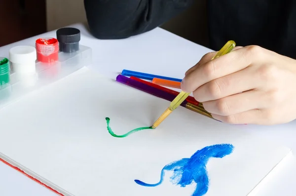 Mano izquierda dibuja pincel con pintura verde sobre papel en álbum con se —  Fotos de Stock