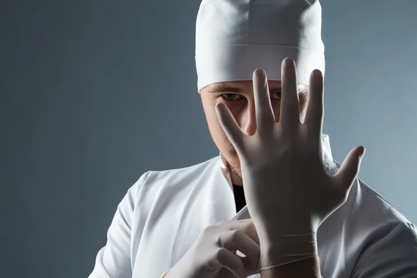 Male doctor in cap with beard wear rubber medical gloves in cont — Stock Photo, Image