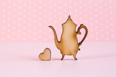 Pembe bir arka plan üzerinde küçük kalpli çaydanlık ahşap simgesi