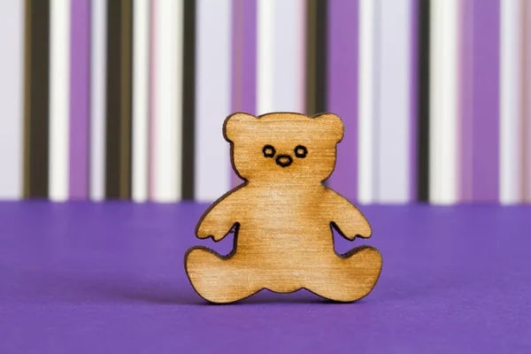 Wooden icon of Teddy bear on purple striped background — Stock Photo, Image