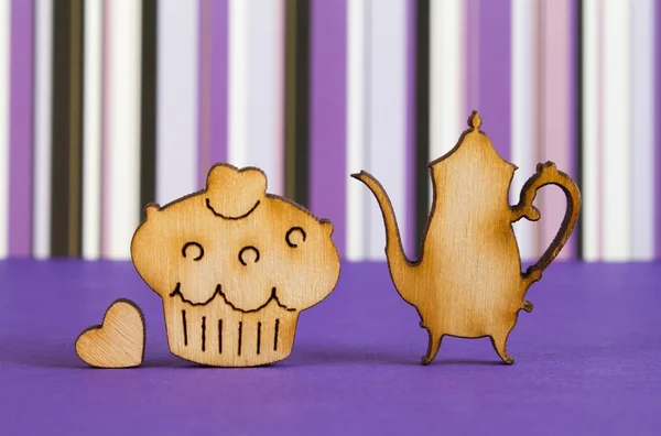 Wooden icons of cake and teapot with little heart on purple stri — Stock Photo, Image