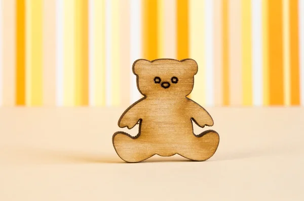 Wooden icon of Teddy bear on orange striped background — Stock Photo, Image