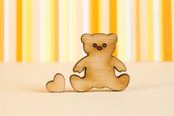 Wooden icon of Teddy bear with little heart on orange striped ba — Stock Photo, Image