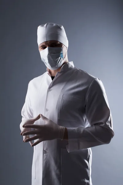 Mężczyzna lekarz w WPR i maska zakładać gumowe rękawice medyczne w contra — Zdjęcie stockowe